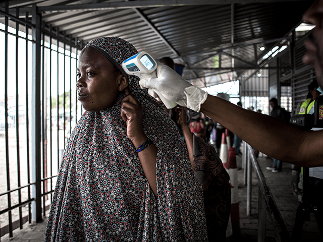 A woman gets her temperature measured at an Ebola screening station as she enters the Demo