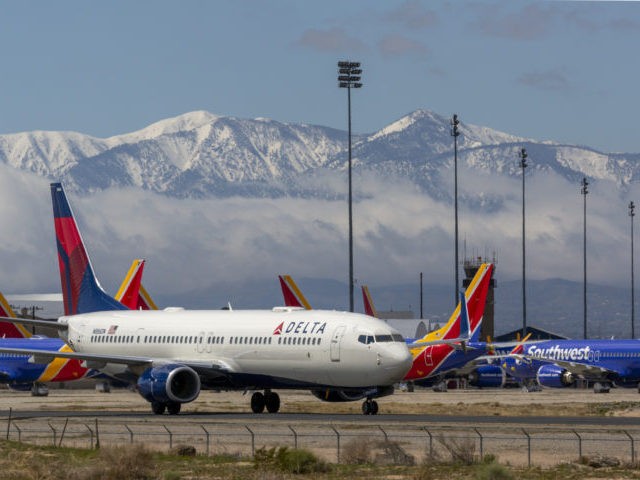 VICTORVILLE, CA - MARCH 24: A Delta Air Lines jet taxis passes Southwest Airlines jets to be parked with a growing number of jets at Southern California Logistics Airport (SCLA) on March 24, 2020 in Victorville, California. As the coronavirus pandemic grows, exponentially increasing travel restrictions and the numbers of …