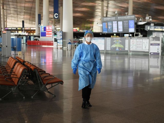 A worker wearing protective clothing walks to a temperature checking station at the airport in Beijing on June 18, 2020. - Travel restrictions were placed on nearly half a million people near Beijing on June 18 as authorities rushed to contain a fresh outbreak of the coronavirus with a mass test-and-trace effort and lockdowns in parts of the Chinese capital. Beijing's airports cancelled two-thirds of all flights on June 17 and flight-tracking websites showed around 140 passenger flights had landed or departed so far on June 18. (Photo by GREG BAKER / AFP) (Photo by GREG BAKER/AFP via Getty Images)