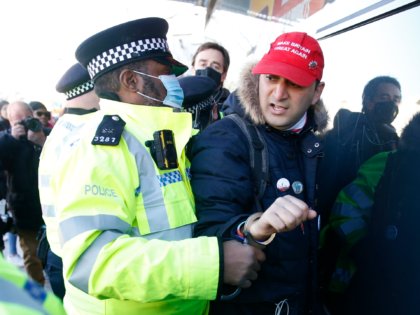 LONDON, ENGLAND - JANUARY 09: A protester wearing a "Make Britain Great Again" baseball cap is detained by Police on Clapham high street during the anti-lockdown demonstration on January 9, 2021 in London, England. Chief Medical Officer Chris Whitty has filmed an advert for HM Government warning that people should …