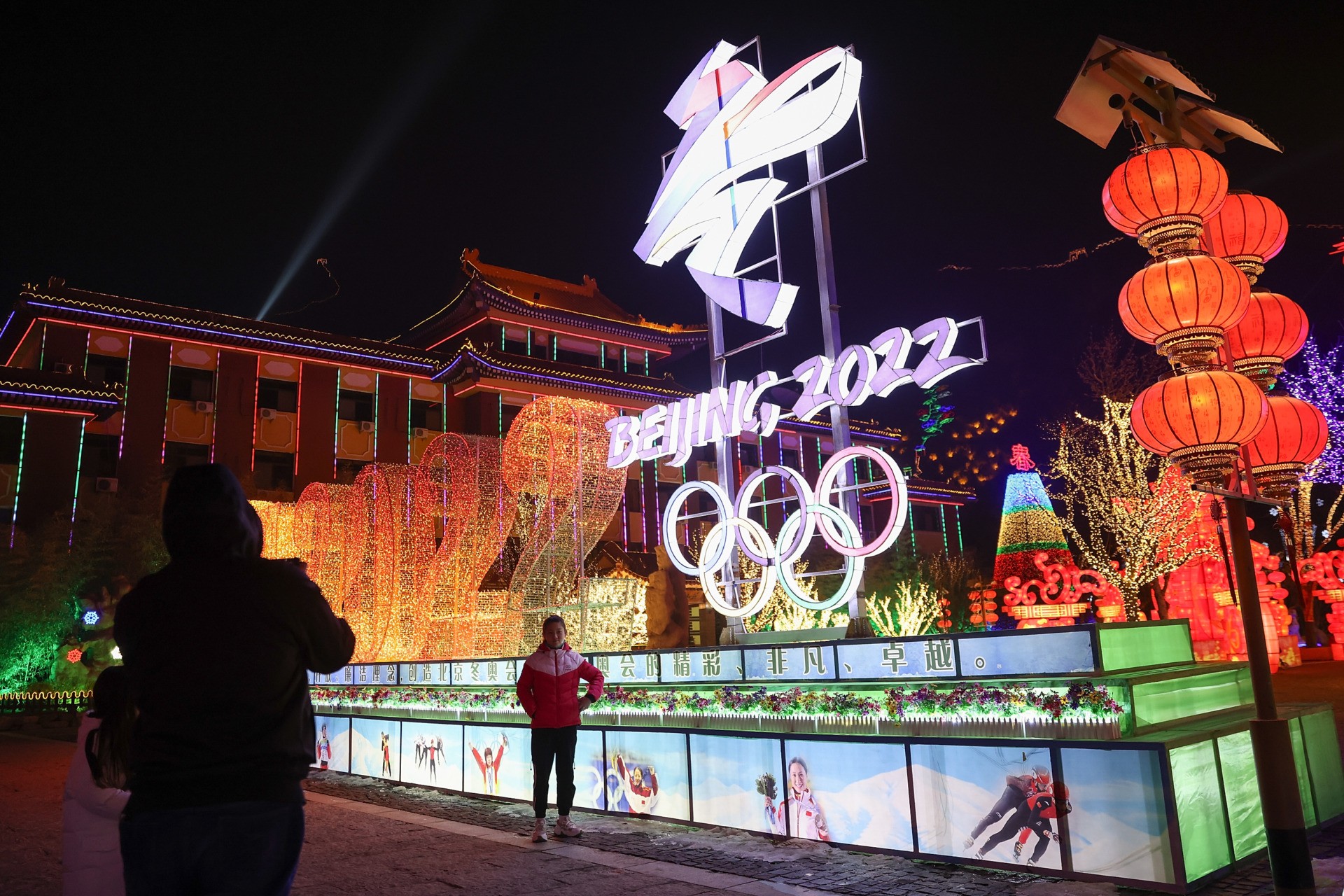 BEIJING, CHINA - FEBRUARY 26: People wear protective masks as they walk front the logos of the 2022 Beijing Winter Olympics at Yanqing Ice Festival on February 26, 2021 in Beijing, China. The Festival comes at the final day of the Chinese Lunar New Year celebrations. (Photo by Lintao Zhang/Getty Images)