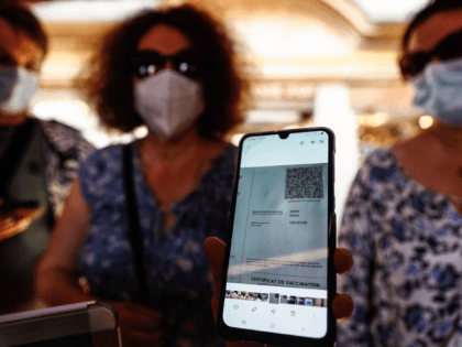 A woman shows her health pass as she arrives at a restaurant in Mont-Saint-Michel, in Normandy, northwestern France, on July 22, 2021. - French cinemas, museums and sports venues began asking visitors July 21, to furnish proof of Covid-19 vaccination or a negative test as the country, which is in …