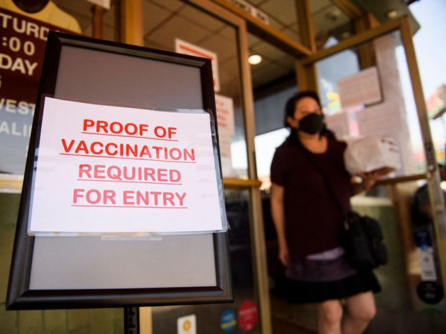 A sign stating proof of a Covid-19 vaccination is required is displayed outside of Langer'