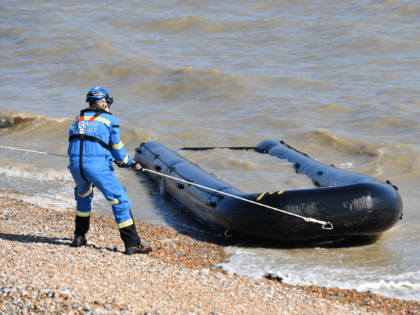 Members of the HM Coastguard remove a waterlogged, discarded boat, that had washed up on a beach in Lydd on Sea, near to where migrants have been arriving, in southeast England on September 8, 2021. (Photo by JUSTIN TALLIS / AFP) (Photo by JUSTIN TALLIS/AFP via Getty Images)