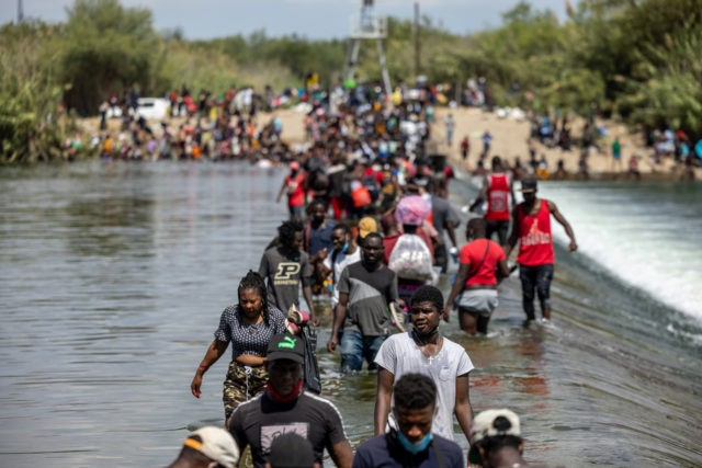 DEL RIO, TX - SEPTEMBER 18: Migrants cross the Rio Grande River near a temporary migrant camp under the international bridge on September 18, 2021 in Del Rio, Texas. The temporary migrant camp under the international bridge in Del Rio, TX has rapidly grown to more than 14,000 people and …