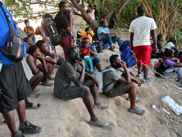 Haitian migrants sit on the banks of the Rio Grande river before crossing the Mexico-US border at Ciudad Acuna, Coahuila state, Mexico, on September 23, 2021. - The US special envoy to Haiti resigned on September 23 two months after his appointment, denouncing the Biden administration's deportation of Haitian migrants …