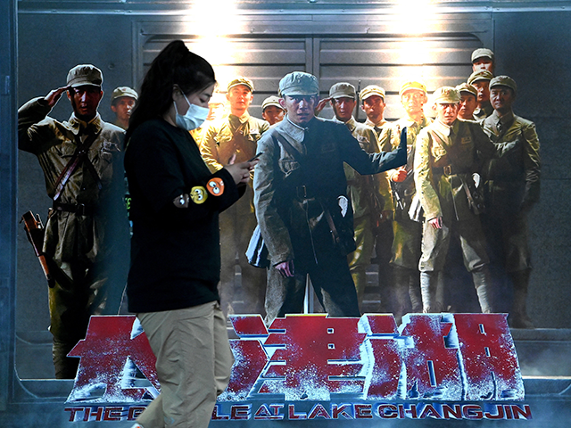 A woman walks past a movie promotion poster or "The Battle of Lake Changjin" at a mall in