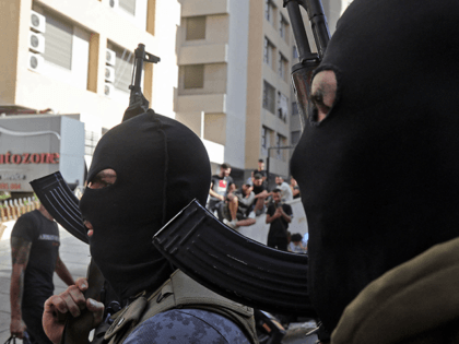 Masked Shiite fighter from Hezbollah and Amal movements walk with Kalashnikov assault rifl