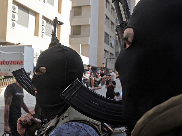 Masked Shiite fighter from Hezbollah and Amal movements walk with Kalashnikov assault rifles amidst clashes in the area of Tayouneh, in the southern suburb of the capital Beirut, on October 14, 2021. - Gunfire killed several people and wounded 20 at a Beirut rally organised by the Shiite Hezbollah and …