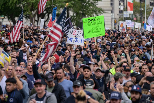 Municipal workers hold placards and shout slogans during a protest against the covid-19 va