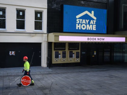 LONDON, UNITED KINGDOM - NOVEMBER 05: A construction worker carries a stop sign past a closed cinema in Leicester Square on November 05, 2020 in London, United Kingdom. England enters its second national coronavirus lockdown today. People are still permitted to exercise with one other person, takeaway food is permitted …