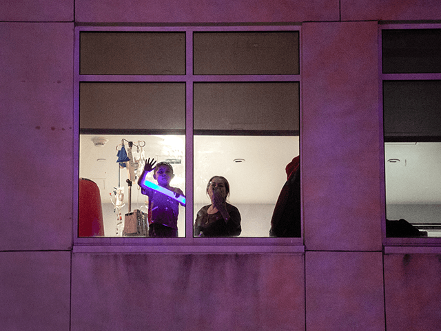 A child watches from a hospital room as a convoy of first responders arrives to a children