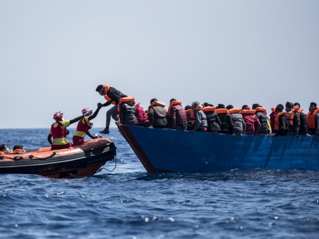 AT SEA - MARCH 29: Two lifeguards from the Spanish NGO Open Arms transfers a man from a wooden boat with 84 migrants of different nationalities to the RHIB (rigid-hulled inflatable boat) during the rescue on March 29, 2021 in At Sea, Unspecified. The Spanish NGO Open Arms rescued passengers …