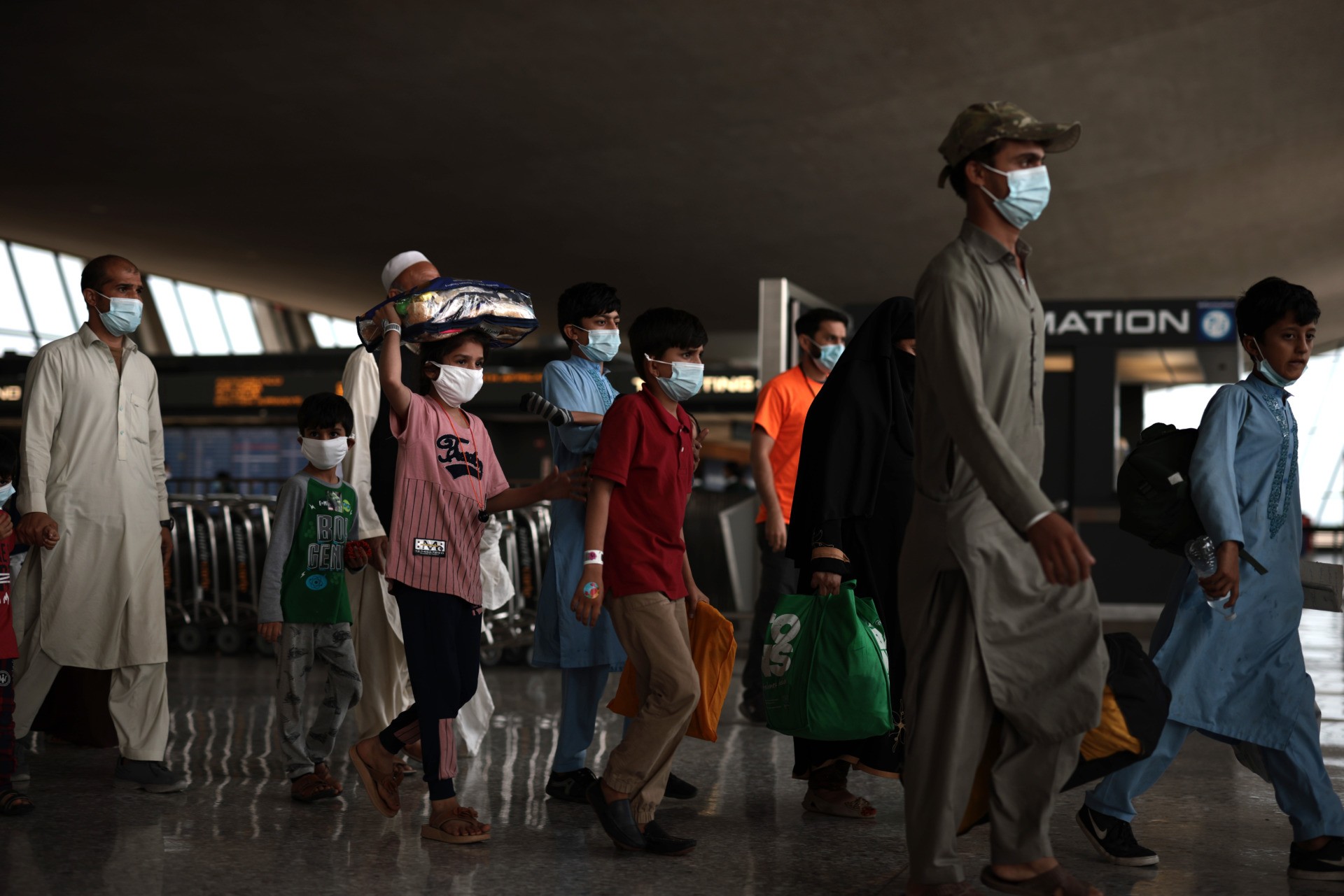 DULLES, VIRGINIA - AUGUST 31: Refugees walk through the departure terminal to a bus at Dulles International Airport after being evacuated from Kabul following the Taliban takeover of Afghanistan on August 31, 2021 in Dulles, Virginia. The Department of Defense announced yesterday that the U.S. military had completed its withdrawal from Afghanistan, ending 20 years of war. (Photo by Anna Moneymaker/Getty Images)
