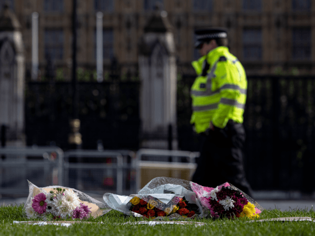 LONDON, ENGLAND - OCTOBER 16: A police officer walks past floral tributes left outside Parliament on October 16, 2021 in London, England. Counter-terrorism officers are investigating the murder of Sir David Amess, the Conservative MP for Southend West, who was stabbed to death during his constituency surgery yesterday around midday. …