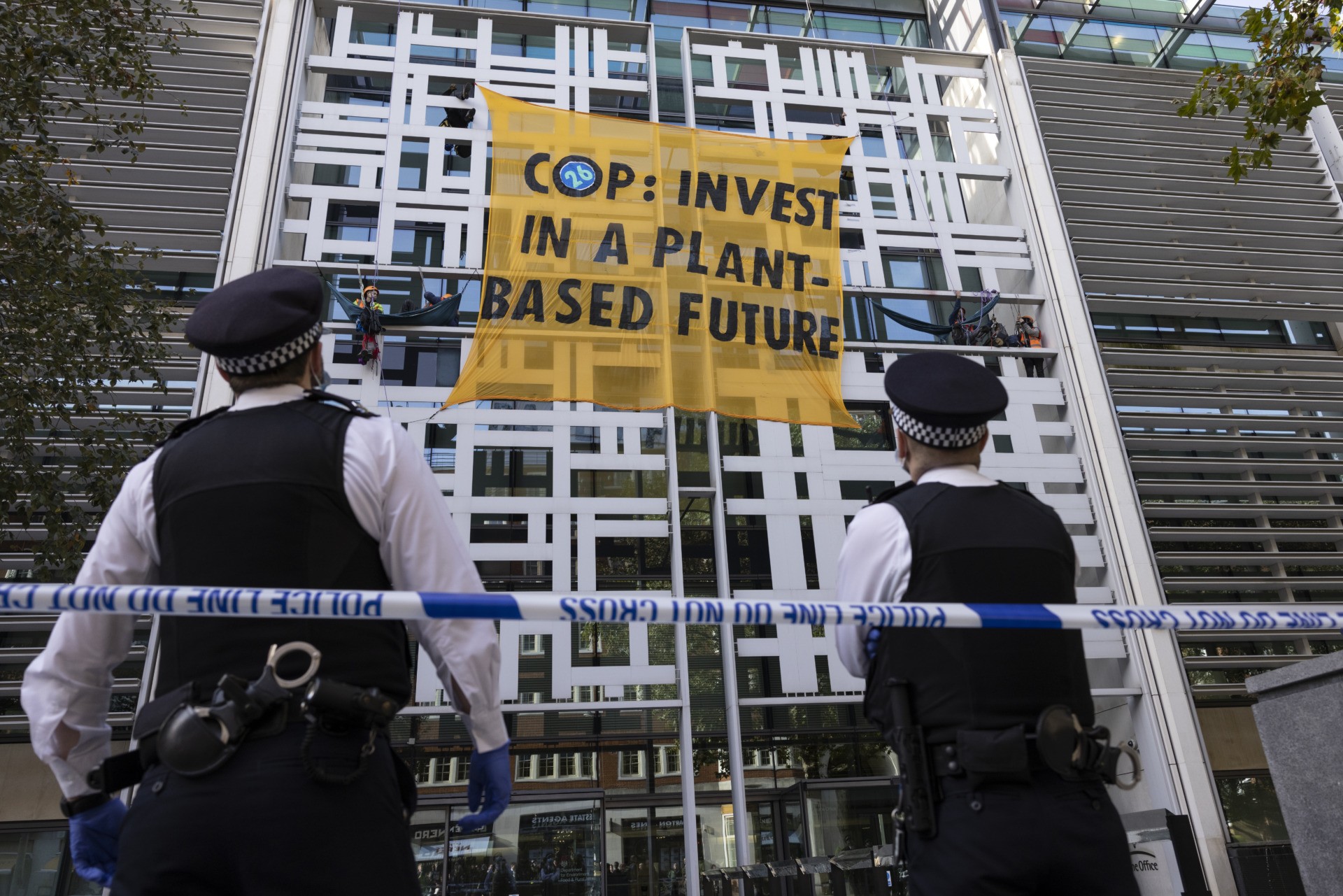 LONDON, ENGLAND - OCTOBER 26: Police move in to cut down a banner as Environmental activists remain at the Home Office on October 26, 2021 in London, England. Protesters dropped a banner from the building reading "COP: Invest In A Plant-Based Future," referring to the upcoming United Nations Conference On Climate Change (COP26) in Glasgow that starts this weekend. (Photo by Dan Kitwood/Getty Images)