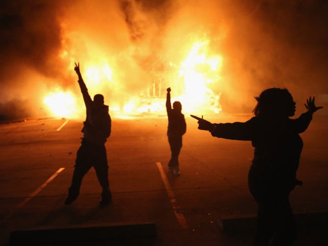FERGUSON, MO - NOVEMBER 24: Demonstrators celebrate as a business burns after it was set