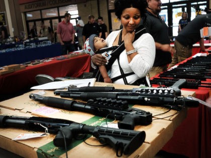 A woman admires weapons at a gun show where thousands of different weapons are displayed f