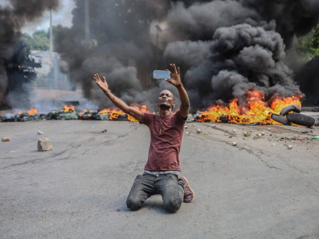 OPSHOT - A man films himself in front of tires on fire during a general strike launched by several professional associations and companies to denounce insecurity in Port-au-Prince on October 18, 2021. - A nationwide general strike emptied the streets of Haiti's capital Port-au-Prince on Monday with organisers denouncing the …