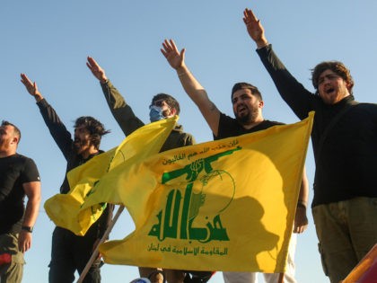 Supporters of the Lebanese Shiite movement Hezbollah perform a salute as they stand behind motorcycles carrying the group's flags in the southern Lebanese district of Marjayoun on the border with Israel on May 25, 2020. (Mahmoud Zayyat/AFP via Getty Images)