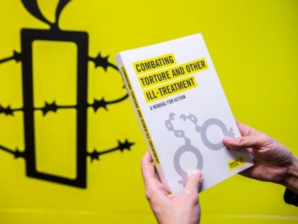 An Amnesty International employee holds one of their publications next to their logo in the Hong Kong office on October, 2021, as the Human Rights organisation announces it will be closing its offices by the end of 2021 citing Beijings enacted national security law as a reason. (Isaac Lawrence/AFP via …