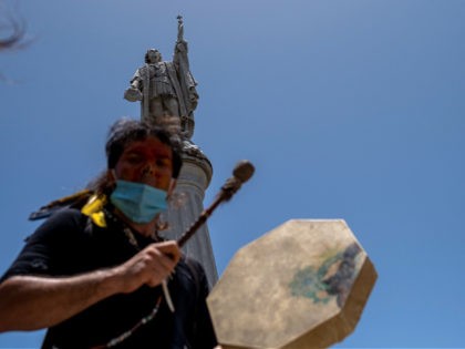 A member of the Council in Defense of the Indigenous Rights of Boriken marches in front of a Christopher Columbus statue during a march through Old San Juan, Puerto Rico on July 11, 2020. - The protesters demanded the removal of symbols honoring colonial oppression, starting with statues including those …