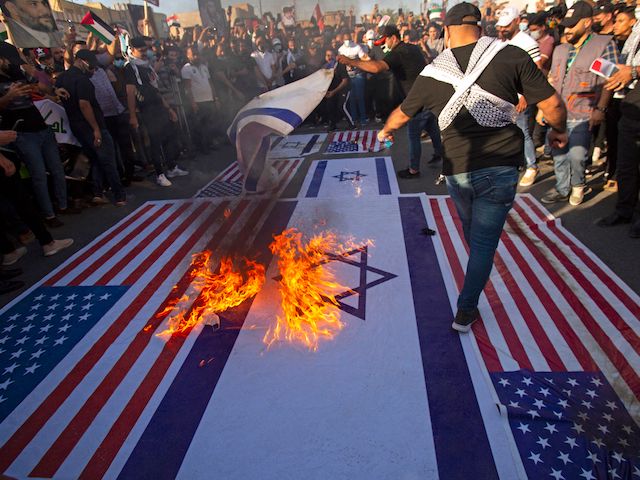 Supporters of Iraqi Shiite cleric Muqtada al-Sadr burn the American and Israeli flags during a march in solidarity with the Palestinians, in the southern Iraqi city of Basra on May 15, 2021. (Hussein Faleh/AFP via Getty Images)