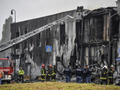 Firefighters work on the site of a plane crash, in San Donato Milanese suburb of Milan, Italy, Sunday, Oct. 3, 2021. According to media reports, a small plane carrying five passengers and the pilot crashed into an apparently vacant office building in a Milan suburb. Their fates were not immediately …