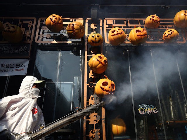 A health official from Yongsan district, wearing personal protective equipment (PPE), sprays anti-septic solution at outside stores in an alley of Itaewon district to prevent the spread of coronavirus ahead of Halloween on October 29, 2021 in Seoul, South Korea. (Chung Sung-Jun/Getty Images)