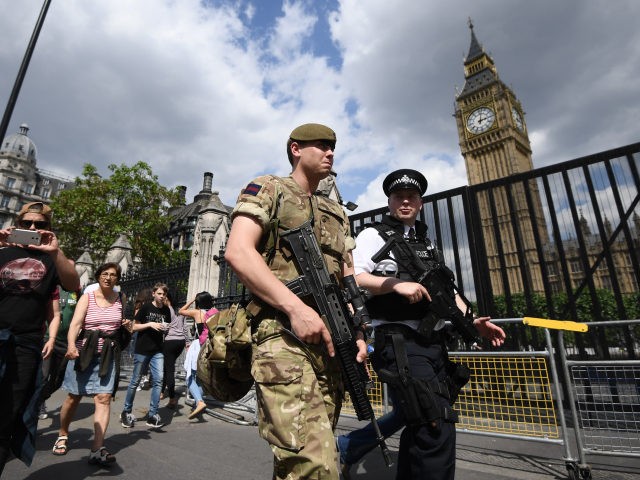 LONDON, ENGLAND - MAY 24: An armed soldier and an armed police officer patrol outside the