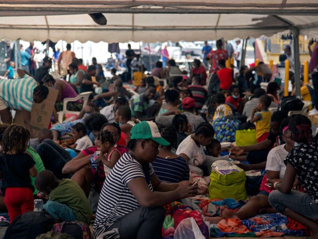Haitian migrants remain outside a migrant shelter where they await their immigration resol