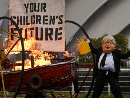 GLASGOW, SCOTLAND - OCTOBER 27: An activist from Ocean Rebellion dressed as Boris Johnson sets light to the sail of a small boat as they protest next to the River Clyde opposite the COP26 site on October 27, 2021 in Glasgow, Scotland. The Extinction Rebellion-affiliated group staged their protest on …
