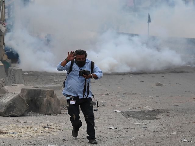 A photo-journalist reacts while riot policemen clash with supporters of Tehreek-e-Labbaik