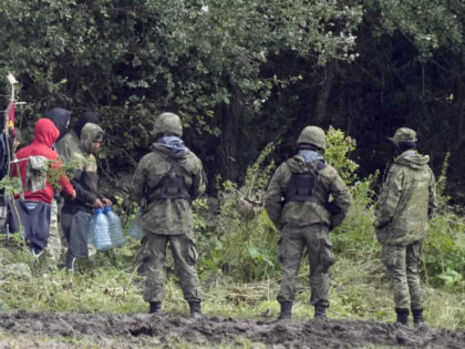 FILE - In this Sept. 1, 2021 file photo, migrants stuck along the Poland-Belarus border carry plastic water bottles as they are surrounded by Polish forces in Usnarz Gorny, Poland. Officials in Poland said Monday, Oct. 25, 2021, that two soldiers have been lightly hurt when a group of some …