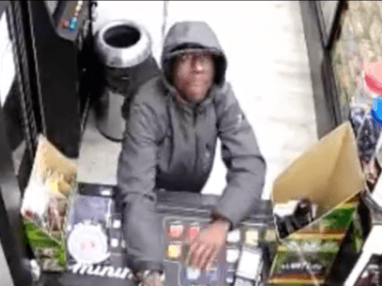 A suspect wanted for attempted robbery reaches over the counter on Saturday, October 23, 2021, inside of Convenience Smoke Shop, Bronx, NYC.(@NYPDTips/Twitter)