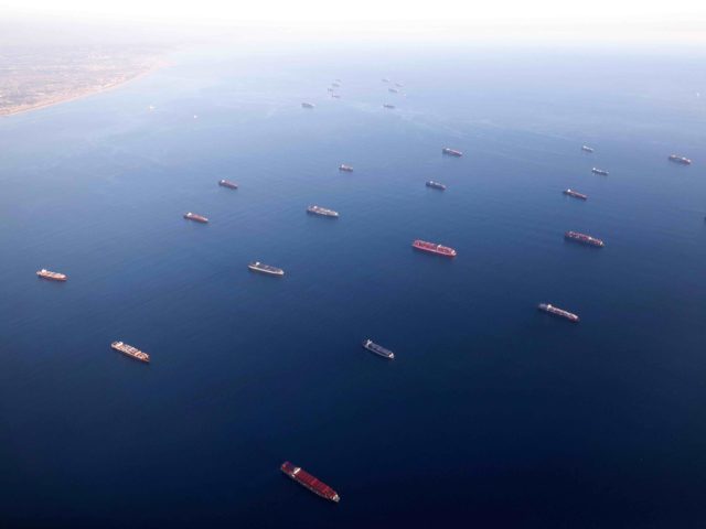 In an aerial view, container ships are anchored by the ports of Long Beach and Los Angeles