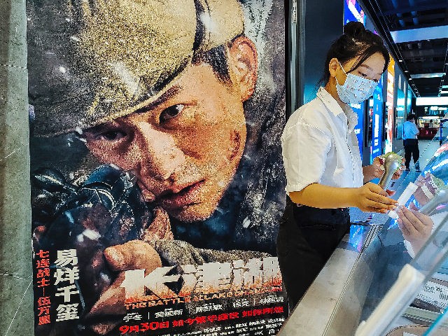 WUHAN, CHINA - OCTOBER 2: (CHINA OUT) Cinema employees sell Haagen-Dazs ice cream as the movie poster of “The Battle At Lake Changjin" is seen in a cinema on October 2, 2021 in Wuhan, Hubei province, China. In three days after its release, the film grossed more than 1 billion …