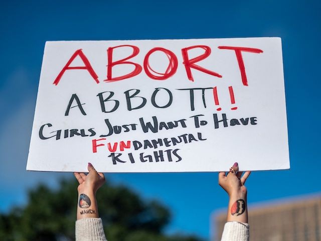 A woman holds a sign in reference to Texas Governor Greg Abbott as protesters take part in the Women's March and Rally for Abortion Justice in Austin, Texas, on October 2, 2021. (Sergio Flores/AFP via Getty Images)