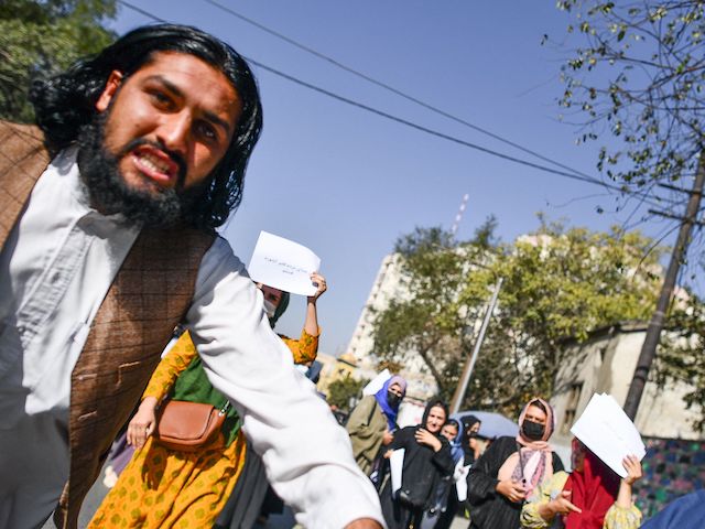 A Taliban member (L) attacks a foreign photographer covering a women's rights protest in Kabul on October 21, 2021. (Bulent Kilic/AFP via Getty Images)