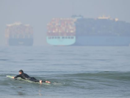 A surfer waits for waves at Huntington Beach, California on Setember 25, 2021 as container