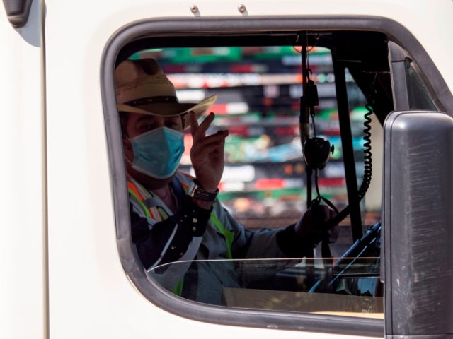 A trucker waves his thanks after picking up free food provided by Teamsters union members and the Los Angeles Regional Food Bank to hundreds of port truck drivers impacted by the coronavirus COVID-19 crisis, during a mobile drive-through food pantry, April 22, 2020 in Long Beach, California. - The risk …