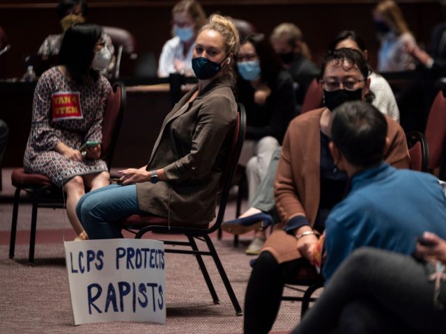 A woman sits with her sign during a Loudoun County Public Schools (LCPS) board meeting in Ashburn, Virginia on October 12, 2021. - Loudoun county school board meetings have become tense recently with parents clashing with board members over transgender issues, the teaching of critical race theory (CRT) and Covid-19 …