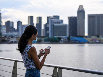 This picture taken on May 7, 2021 shows an advertising executive who wanted to be known as Erica checking her mobile phone along the Marina Bay promenade in Singapore. - Erica is among a growing number of women travelling overseas to get their eggs frozen, as people in the work-obsessed …