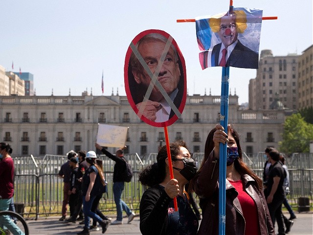 Demonstrators march with posters depicting Chilean President Sebastian Pinera during a teachers' protest against the government, outside La Moneda presidential palace in Santiago, on October 13, 2021. - Chile's opposition on Wednesday moved to impeach the country's president, Sebastian Pinera, for the controversial sale of a mining company through a firm owned by his children, which appeared in the Pandora Papers leaks, a congressman said. (Photo by CLAUDIO REYES / AFP) (Photo by CLAUDIO REYES/AFP via Getty Images)