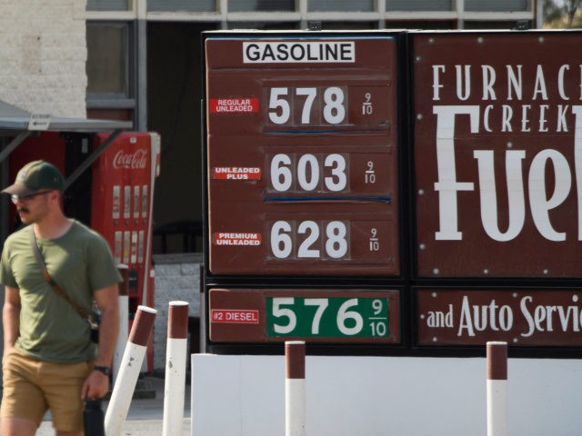 A pedestrian walks past gas station fuel prices above $5 and $6 per gallon at Death Valley