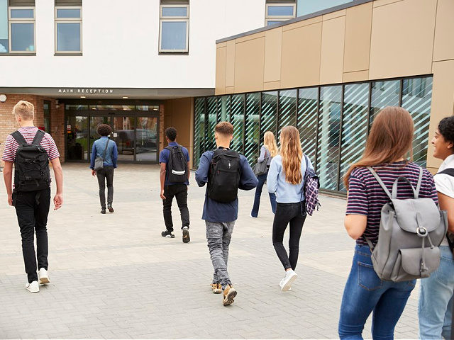 Rear View Of High School Students Walking Into College Building Together - stock photo