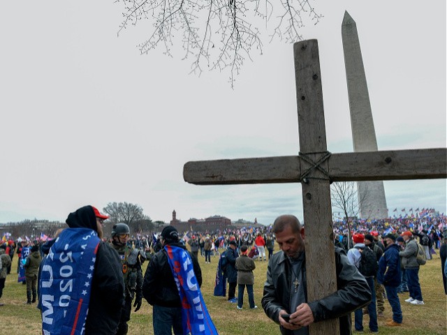 A man holds a large wooden cross near the Washington Monument during a rally in support of US President Donald Trump in Washington DC on January 6, 2021. - Donald Trump's supporters stormed a session of Congress held today, January 6, to certify Joe Biden's election win, triggering unprecedented chaos and violence at the heart of American democracy and accusations the president was attempting a coup. (Photo by Joseph Prezioso / AFP) (Photo by JOSEPH PREZIOSO/AFP via Getty Images)