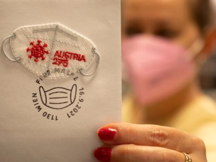 A post worker holds a special edition post stamp, in the shape of a face mask and made out of the same fabric, issued by Austrian Post dedicated to the novel coronavirus (Covid-19) period pictured in Vienna on September 16, 2021. (Photo by JOE KLAMAR / AFP) (Photo by JOE …