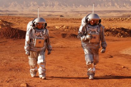 A couple of trainee astronauts walk in their spacesuits during a training mission for plan