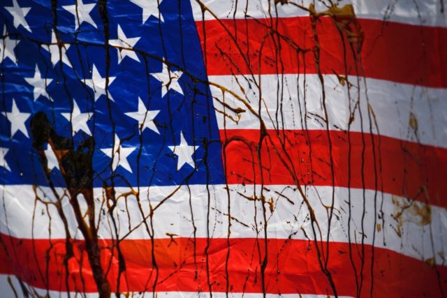 A US flag is stained with a biodegradable substance masquerading as "oil" by demonstrators